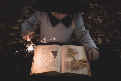 女孩一边看书一边拿着点燃的火花